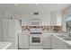 All-white kitchen showcasing modern appliances and a mosaic tile backsplash at 400 El Camino Dr # 101, Winter Haven, FL 33884