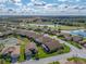 Aerial view of a home with an extended lanai, nestled within a serene neighborhood featuring mature trees and a large lake at 4033 Phoenician Way, Winter Haven, FL 33884