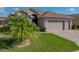 Well-maintained single-story home featuring a lush green lawn, palm tree, and brick driveway at 4033 Phoenician Way, Winter Haven, FL 33884