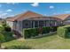 Exterior shot showcasing a house with screened-in patio and pool with manicured hedges in a beautiful, green backyard at 4033 Phoenician Way, Winter Haven, FL 33884