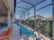 A long screened-in pool and patio area showcasing the blue pool and hedges in the yard at 4033 Phoenician Way, Winter Haven, FL 33884