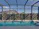 Screened-in pool and patio area featuring a narrow pool surrounded by green plants and clear blue sky at 4033 Phoenician Way, Winter Haven, FL 33884