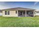 Home's back elevation showcasing a screened lanai and grassy yard at 452 Palastro Ave, Auburndale, FL 33823
