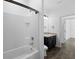 Bathroom with white tiled bathtub with black fixtures, dark cabinets, toilet and sink at 4924 Saint James St, Winter Haven, FL 33881