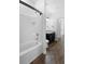 White tiled bathtub with black fixtures, alongside a dark vanity and toilet at 4924 Saint James St, Winter Haven, FL 33881
