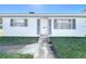 Inviting single-story home featuring a white door, matching shutters, manicured lawn and a concrete walkway leading to the entrance at 720 Fonda Ct # 54, Lakeland, FL 33803