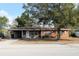 Cozy brick house featuring a covered carport and a well-maintained yard with a large shade tree at 807 S 1St St, Lake Wales, FL 33853