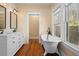 Bathroom with clawfoot tub, double vanity, wood floors, and natural light from large windows at 907 Vistabula St, Lakeland, FL 33801