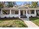 Quaint home with a covered porch adorned with string lights and lush landscaping at 907 Vistabula St, Lakeland, FL 33801