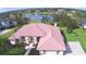Aerial view of a home with a terracotta roof, lush landscaping, and a community lake at 105 Wyndham Dr, Winter Haven, FL 33884