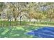 Outdoor basketball court with a blue section, surrounded by green space, mature trees and a partial green fence at 105 Wyndham Dr, Winter Haven, FL 33884