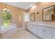 This bathroom features a soaking tub, double vanity with white cabinets, and a decorative chandelier at 105 Wyndham Dr, Winter Haven, FL 33884