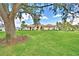 A wide shot showcases a lovely home with a green lawn and mature landscaping beneath a partly cloudy sky at 105 Wyndham Dr, Winter Haven, FL 33884