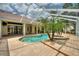This screened-in pool is surrounded by tropical plants and brick pavers at 105 Wyndham Dr, Winter Haven, FL 33884