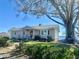 Inviting single-story home featuring mature trees, charming front porch, and a lush lawn leading to the lake at 1050 E Eagle Ave, Eagle Lake, FL 33839