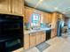 Well-lit kitchen features wood cabinets, black appliances, tile flooring, and a stainless steel sink under a window at 1050 E Eagle Ave, Eagle Lake, FL 33839