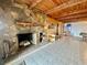 Open living room featuring a stone fireplace, tile floors, and exposed beam ceiling at 1050 E Eagle Ave, Eagle Lake, FL 33839