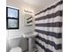 Classic bathroom with pedestal sink, black and white tile, and a striped shower curtain at 1229 Rawls Dr, Lakeland, FL 33801