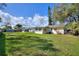 Large grassy backyard showcasing the home's exterior, surrounded by trees, under a partly cloudy sky at 1233 Rawls Dr, Lakeland, FL 33801