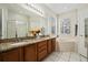 Well-lit bathroom with double sinks, granite countertops, and a soaking tub at 126 Seneca Ln, Davenport, FL 33897