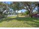 Expansive backyard with large shade trees, swings, and a view of the serene lake at 128 Lake Ring Dr, Winter Haven, FL 33884