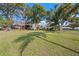 Large backyard with mature trees offering shade, the house, and a glimpse of a lake at 128 Lake Ring Dr, Winter Haven, FL 33884