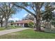Single-story home featuring an attached garage, red tile roof, and mature trees at 128 Lake Ring Dr, Winter Haven, FL 33884
