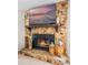 Close-up of a stone fireplace with a wooden mantel, decorative lanterns, and a mounted TV at 128 Lake Ring Dr, Winter Haven, FL 33884