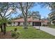 Charming home with a red-tiled roof, mature trees, green lawn, and a long driveway at 128 Lake Ring Dr, Winter Haven, FL 33884