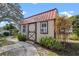 Charming outbuilding with red roof and cream walls surrounded by lush greenery and a stone pathway at 128 Lake Ring Dr, Winter Haven, FL 33884