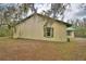 Side view of yellow house with a green metal roof and green shutters at 151 W Hamlin Trl, Frostproof, FL 33843