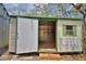 A white and green shed with an open door and one window displays the storage space of this property at 151 W Hamlin Trl, Frostproof, FL 33843