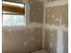 Unfinished bedroom with exposed drywall and a window overlooking the yard at 1928 Old Apopka Rd, Apopka, FL 32703