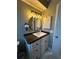 Bathroom vanity features black countertop, round mirror with decorative light fixture, and storage beneath the sink at 229 Durrell Rd, Winter Haven, FL 33884