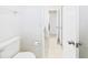 Bright bathroom with a white toilet, an open door, and tile flooring at 31 Wagon Cir, Kissimmee, FL 34743