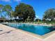 Large community pool surrounded by lounge chairs, umbrellas, and lush landscaping at 37 Enclave Dr, Winter Haven, FL 33884