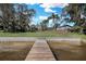 Wooden dock leading to waterfront property with expansive lawn and mature trees at 3943 Chambers St, Lake Wales, FL 33898