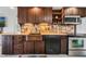 Cozy kitchen featuring rustic stone backsplash, a copper sink, dark wood cabinetry, and modern appliances at 3943 Chambers St, Lake Wales, FL 33898