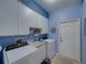 Bright laundry room with blue walls, cabinets, sink, washer and dryer at 4080 Ashton Club Dr, Lake Wales, FL 33859