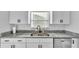 Updated kitchen features a stainless steel sink, modern faucet, granite countertops, and white cabinets at 433 Carleton St, Lakeland, FL 33803