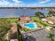 Aerial view of the community pool and clubhouse overlooking a serene lake, surrounded by lounge chairs and lush landscaping at 4422 Glenns Lndg, Winter Haven, FL 33884