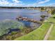 A scenic lake view features a private dock with boats, lush greenery, and a walkway leading to the tranquil waters at 4422 Glenns Lndg, Winter Haven, FL 33884