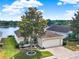 Beautifully landscaped front yard with a large tree, lush lawn, and brick-paved driveway, with a water view at 496 Lake Suzanne Dr, Lake Wales, FL 33859