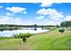 Scenic lake view with lush green lawn and picturesque trees under a bright blue sky with fluffy clouds at 496 Lake Suzanne Dr, Lake Wales, FL 33859
