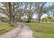 Long gravel driveway leads to a well-kept home surrounded by mature trees at 519 Sharon Hill Ct, Winter Haven, FL 33880