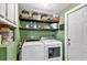 Functional laundry room features modern washer and dryer, shelving, and exterior access at 519 Sharon Hill Ct, Winter Haven, FL 33880