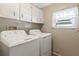 Bright laundry area with white appliances, upper cabinets, and a window at 6053 Southern Oaks Se Dr, Winter Haven, FL 33884
