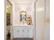 Bathroom with white cabinets, decorative mirror, and adjacent toilet room at 660 Duggers Way, Lake Wales, FL 33859