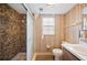A bathroom showcases a glass enclosed tiled shower, brown wallpaper, and marble countertops at 660 Duggers Way, Lake Wales, FL 33859