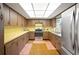 A kitchen showcases wood cabinets, yellow countertops, and neutral tile flooring with stainless steel appliances at 660 Duggers Way, Lake Wales, FL 33859